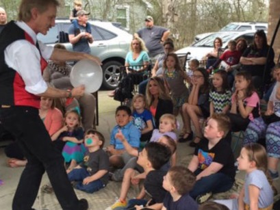 children watching Rodney the Magician performing balloon trick