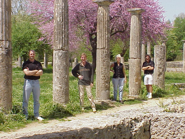 Dave Turner, Rodney Kelley, Donna Moore, Rick Moore standing next to ancient columns in Olympia Greece